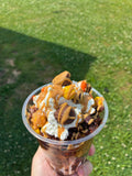 Peanut Butter Madness Dessert Bucket topped with whipped cream, peanut butter drizzle, Reese's Pieces and Peanut Butter Cups