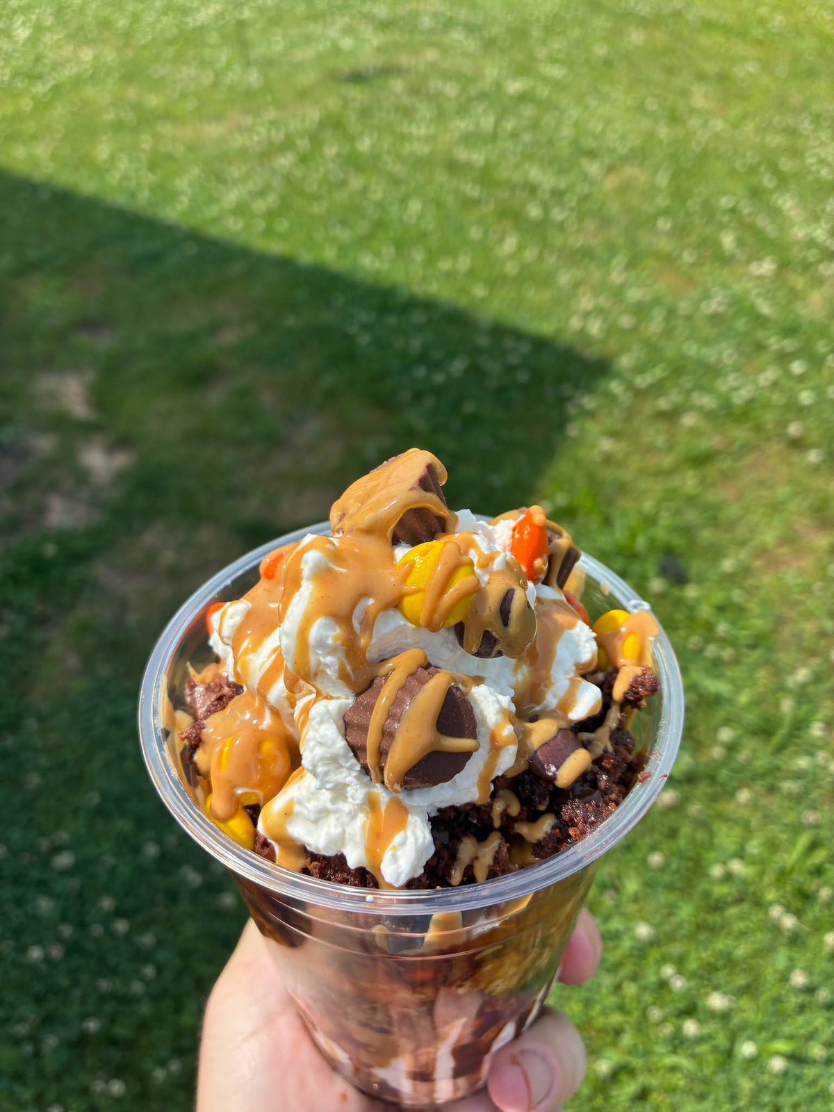 Peanut Butter Madness Dessert Bucket topped with whipped cream, peanut butter drizzle, Reese's Pieces and Peanut Butter Cups