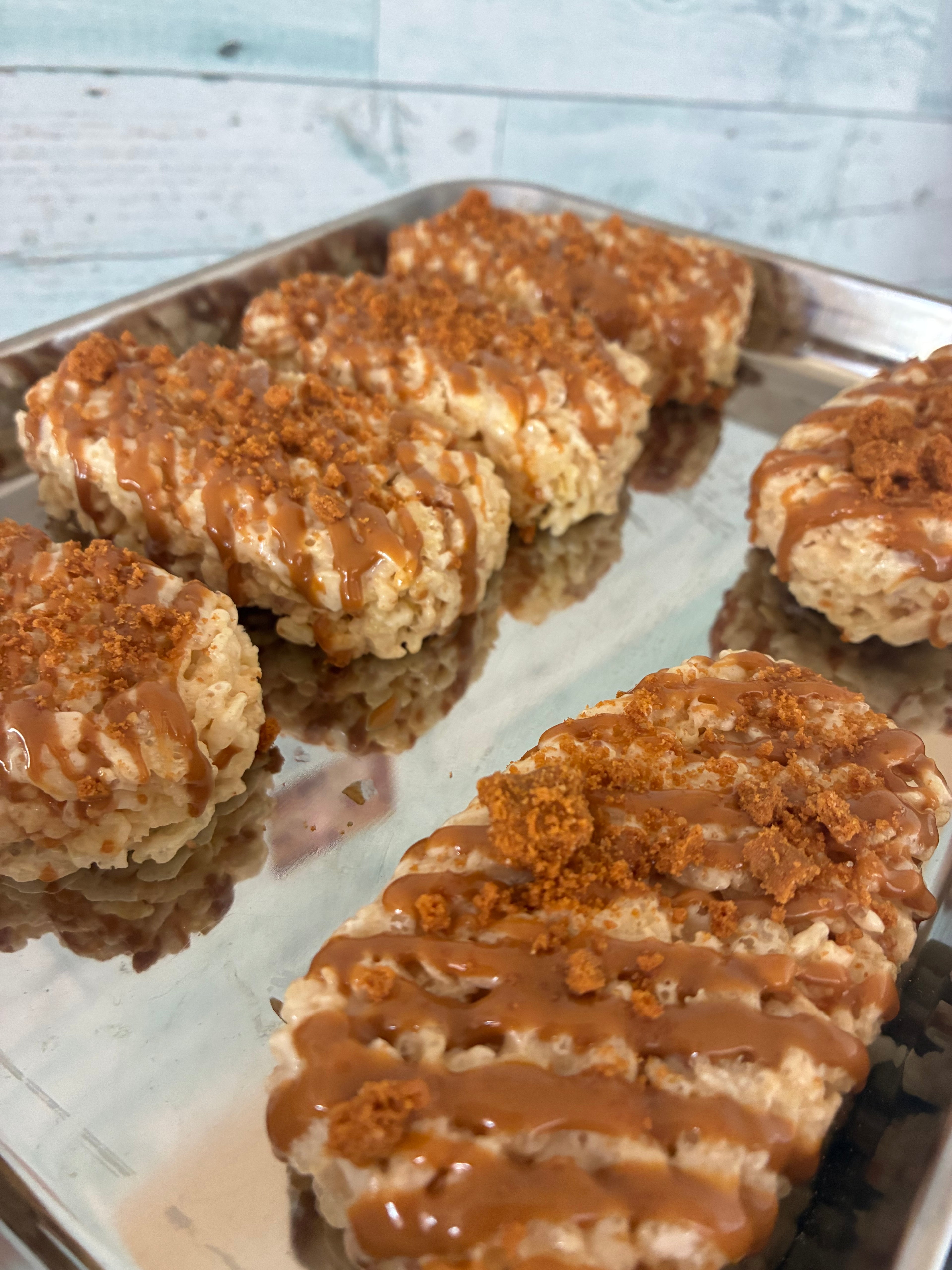 Gourmet homemade Rice Krispie Treats with cookie butter drizzle and crumble topping on a baking tray